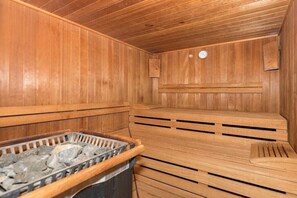Eine Holzsauna mit Bänken und einem steinbefüllten Behälter.