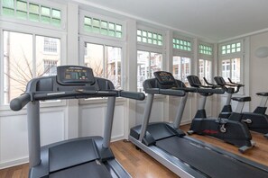 Ein Fitnessraum mit Laufbändern und Ergometer, großen Fenstern und Blick ins Freie.