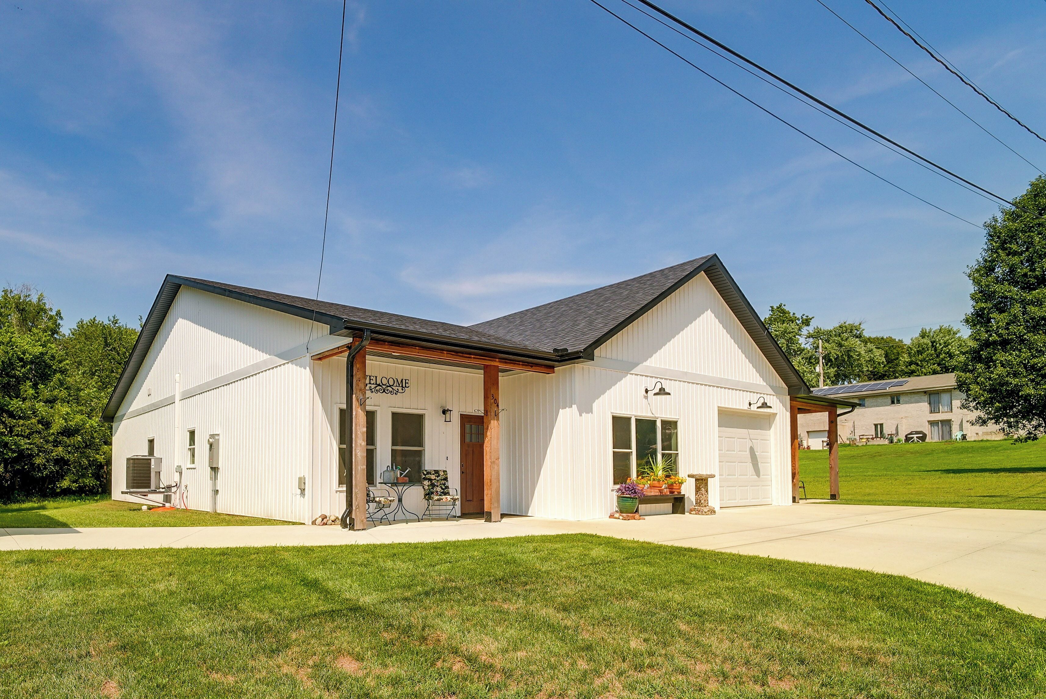 A single-story building with a garage, a covered porch, and a welcoming sign.
