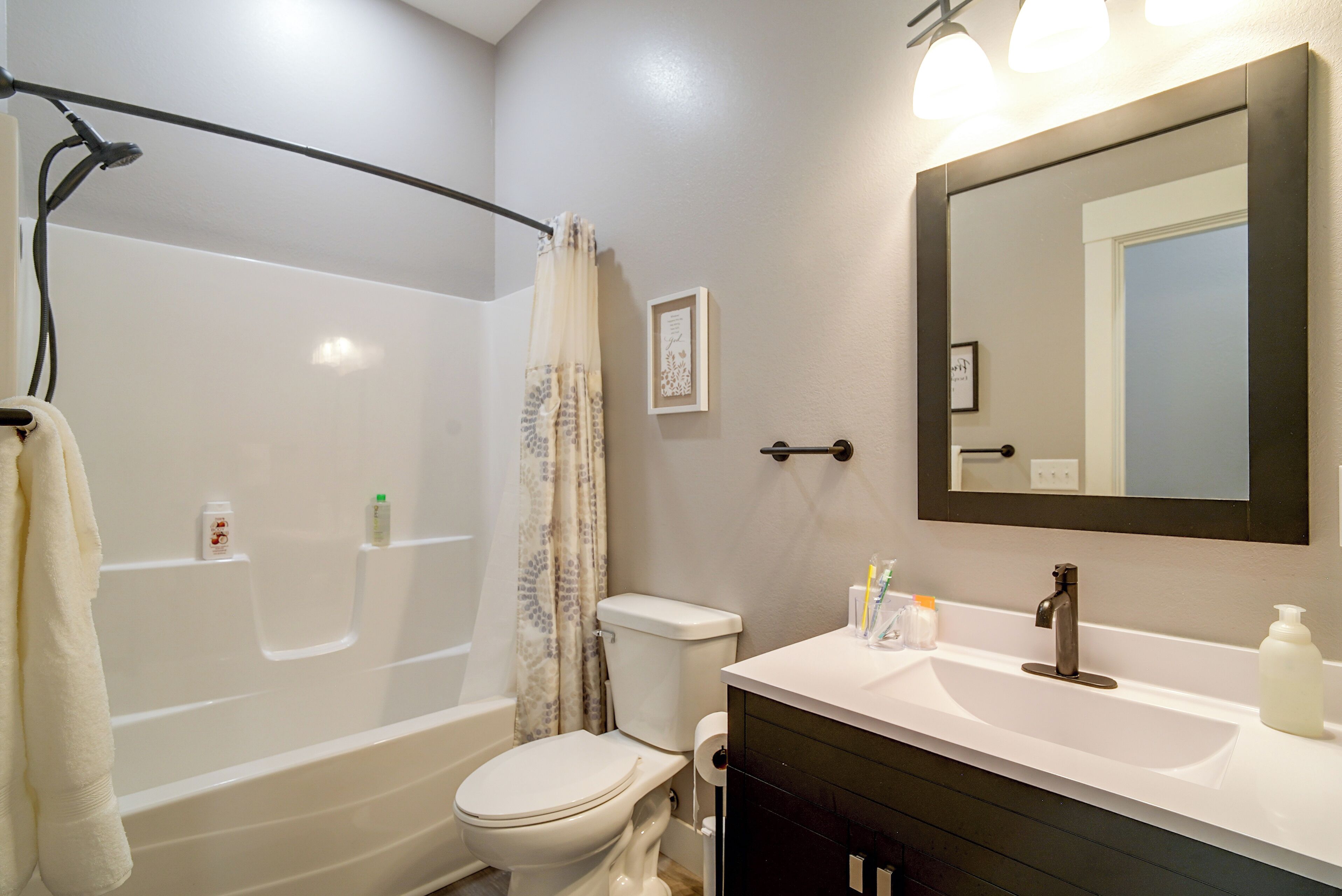 A bathroom with a bathtub, toilet, sink, and a large mirror.