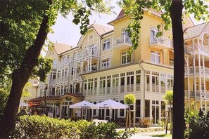 A multi-story building with balconies, outdoor seating, and a café named 'Krombacher'. - Holiday apartment Dünenschloss 319668 (Kühlungsborn)