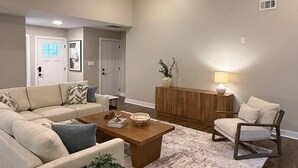 A modern living room with a ceiling fan, a sofa, a coffee table, a side table, and a rug.