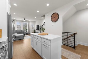 A modern kitchen with white cabinetry, a central island, and a clock on the wall. - South End - Central Charlotte Retreat (Charlotte)