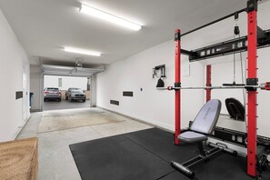 A garage with a weightlifting area, including a bench and squat rack. - South End - Central Charlotte Retreat (Charlotte)