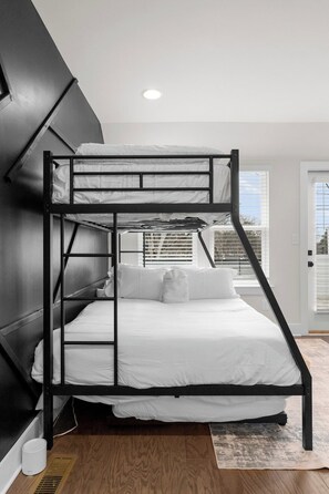 A bunk bed with a black metal frame and white bedding in a room with a sloped ceiling and a window with blinds. - South End - Central Charlotte Retreat (Charlotte)