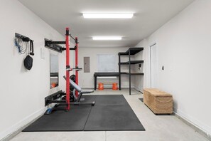Ein Fitnessraum mit Hantelbank, Squat-Rack und Kurzhanteln.