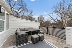 Eine Außenpatio mit einer Eckcouch, einem Tisch und einer Brüstung.