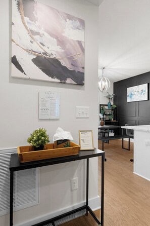 A modern hotel lobby with a large abstract painting, a reception desk with a plant, and a framed review on the wall. - South End - Central Charlotte Retreat (Charlotte)
