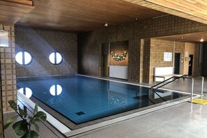 Ein Innenpool mit gefliestem Boden, Holzboden und Backsteinwand.
