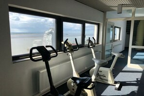 Ein Fitnessraum mit Ergometer und Meerblick.