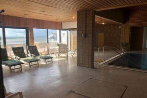 Ein Poolbereich mit Liegestühlen und Blick auf den Strand.