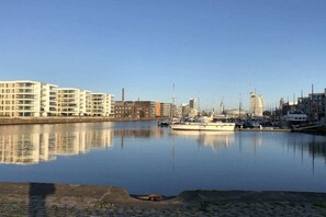 Ein Yachthafen mit Booten, ruhigem Gewässer und Gebäuden im Hintergrund.