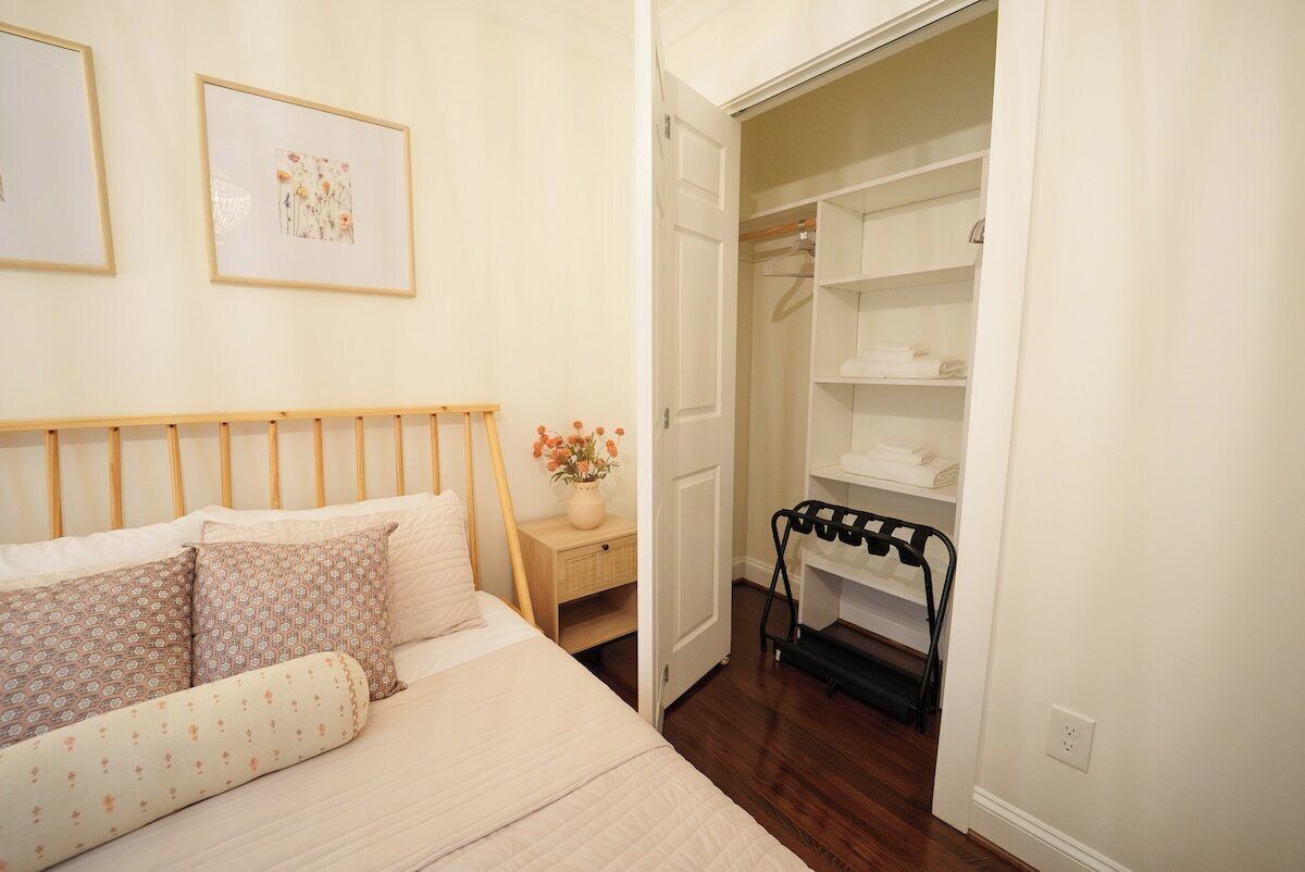 A bedroom with a bed, a nightstand, a closet, and a door leading to another room.