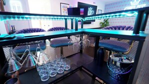 Un espace bar avec un comptoir, des chaises et un téléviseur.