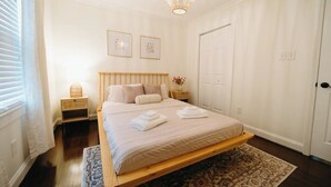 Une chambre à coucher avec un lit, des tables de chevet, un lustre et une porte.