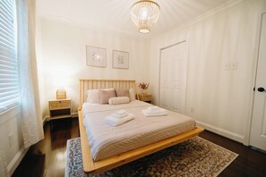 Quarto com cama, mesas de cabeceira, um candelabro e uma porta.