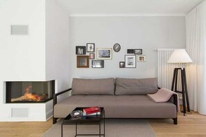 Ein modernes Wohnzimmer mit einer Couch, einem Couchtisch, einem Kamin und einer mit Bilderrahmen versehenen Wand.