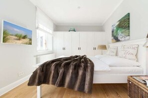 A bedroom with a bed, white cabinets, a window, and a painting on the wall. - Holiday apartment Villa Löwenstein 319574 (Kühlungsborn)