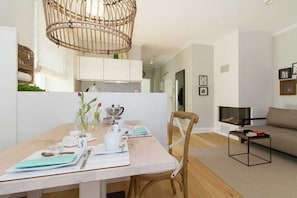 Un espace repas moderne avec une table en bois, des chaises et un luminaire suspendu.