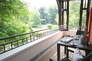 Ein Balkon mit Tisch für Zwei, mit Blick auf einen Garten.