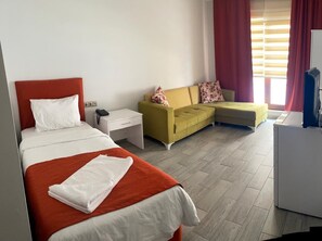 A hotel room with a bed, a sofa, a desk, and a washing machine. - BATIN OTEL (Karabük)