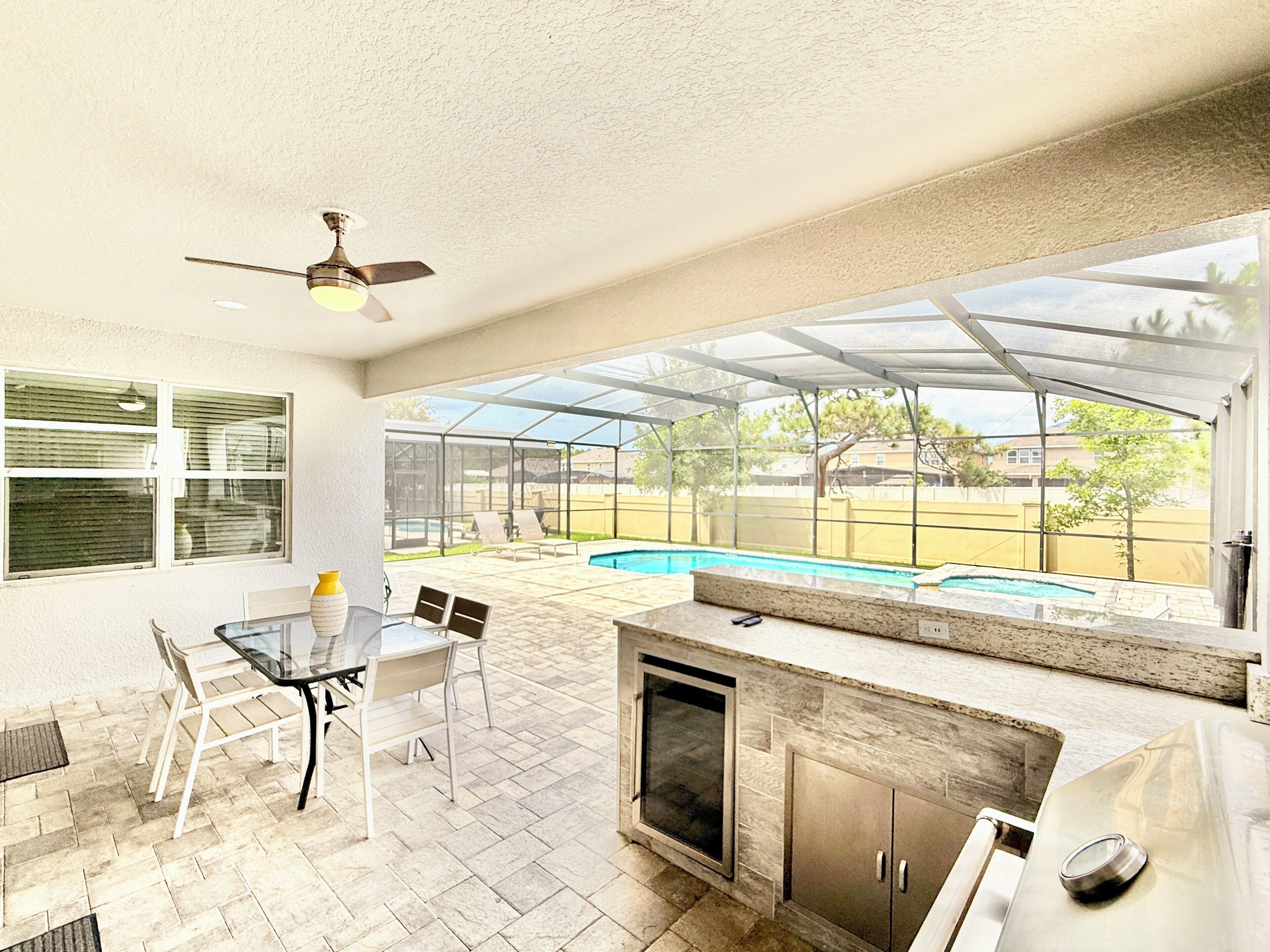 Un patio exterior con cerramiento de vidrio, piscina y zona de barbacoa.