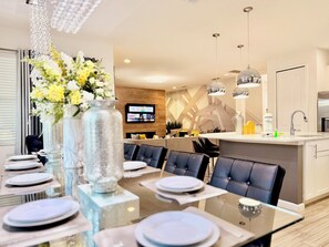 A modern dining area with a glass table, chairs, and a vase of flowers. - Sonoma Resort, 6 Suites, Prime Location, Private Pool, Cinema & Games (Kissimmee)