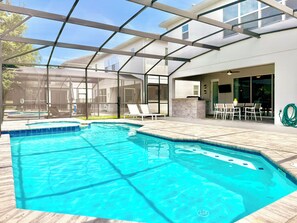 A swimming pool with a glass enclosure, a patio area with outdoor furniture, and a view of a house in the background. - Sonoma Resort, 6 Suites, Prime Location, Private Pool, Cinema & Games (Kissimmee)
