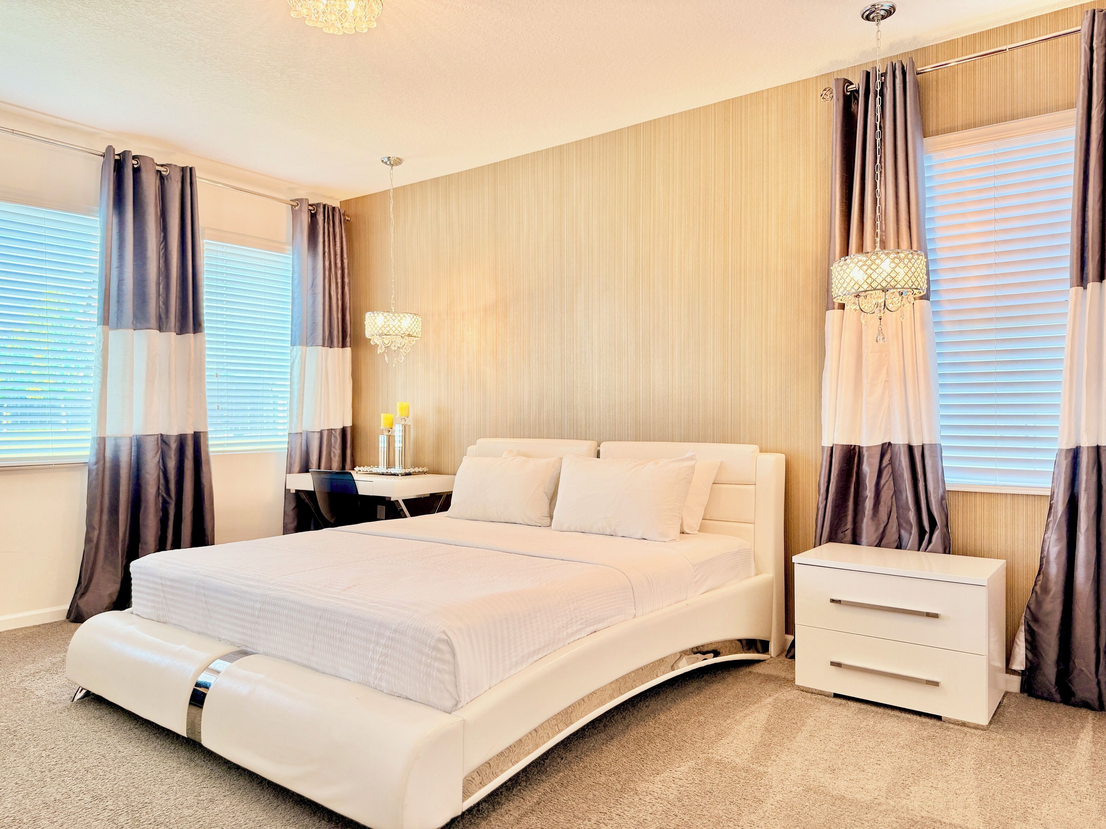 A hotel room with a large bed, bedside tables, a desk, and curtains.
