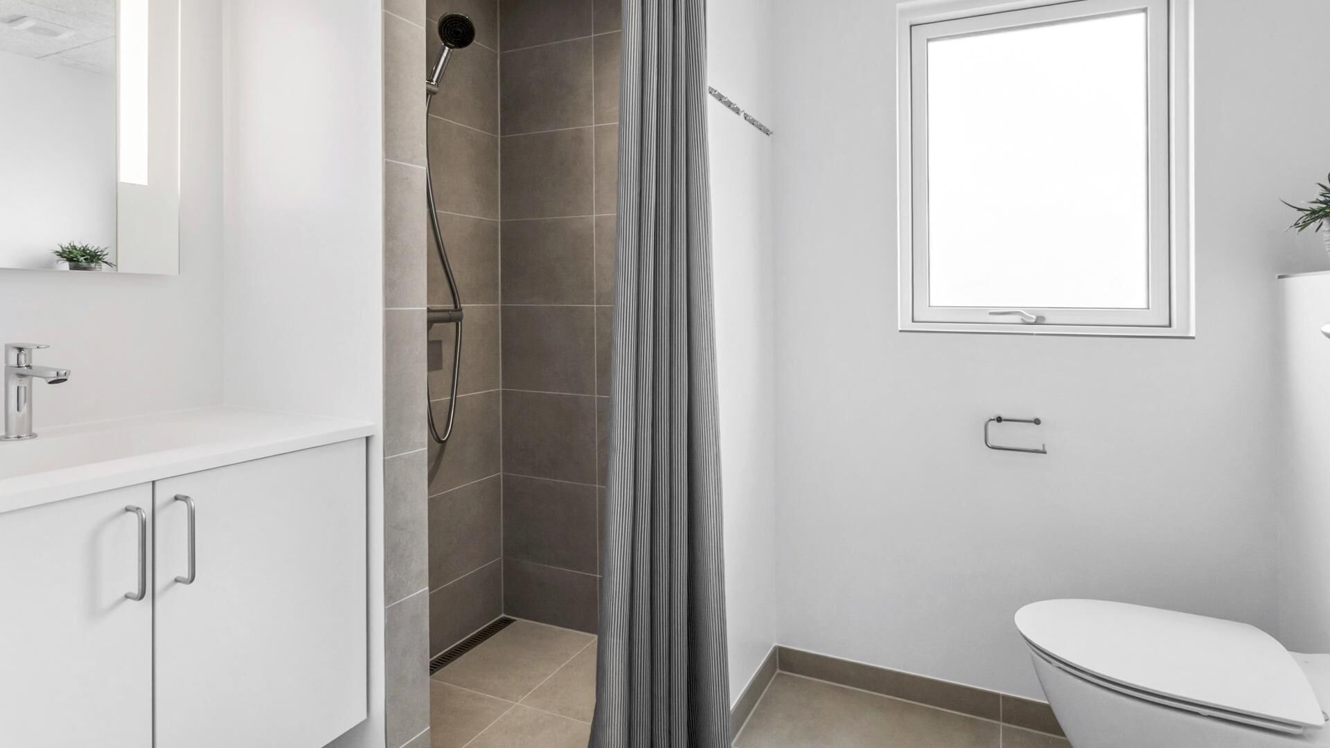 Une salle de bain avec une douche, des toilettes et une fenêtre.