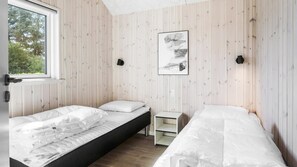A room with two beds, a window, and a wall-mounted artwork.