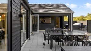Una moderna terrazza esterna con diversi tavoli e sedie, un'area relax coperta e vista sul paesaggio circostante.
