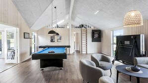 Un ambiente interno moderno con tavolo da biliardo, comodi posti a sedere e una grande finestra.