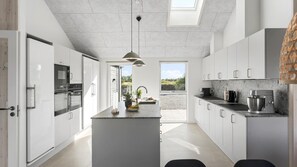 A modern kitchen with a central island, built-in appliances, and a view to the outdoors. - VillaVilla 1001 - Marielyst, Lolland/Falster/møn (Idestrup)