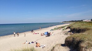 A beach with people sunbathing and swimming, a clear sky, and a grassy dune. - VillaVilla 1002 - Fjellerup, Østjylland (Glesborg)