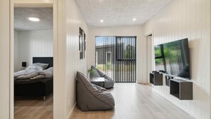 A modern bedroom with a bed, a bean bag, a TV, and a sliding door leading to a balcony. - VillaVilla 1002 - Fjellerup, Østjylland (Glesborg)