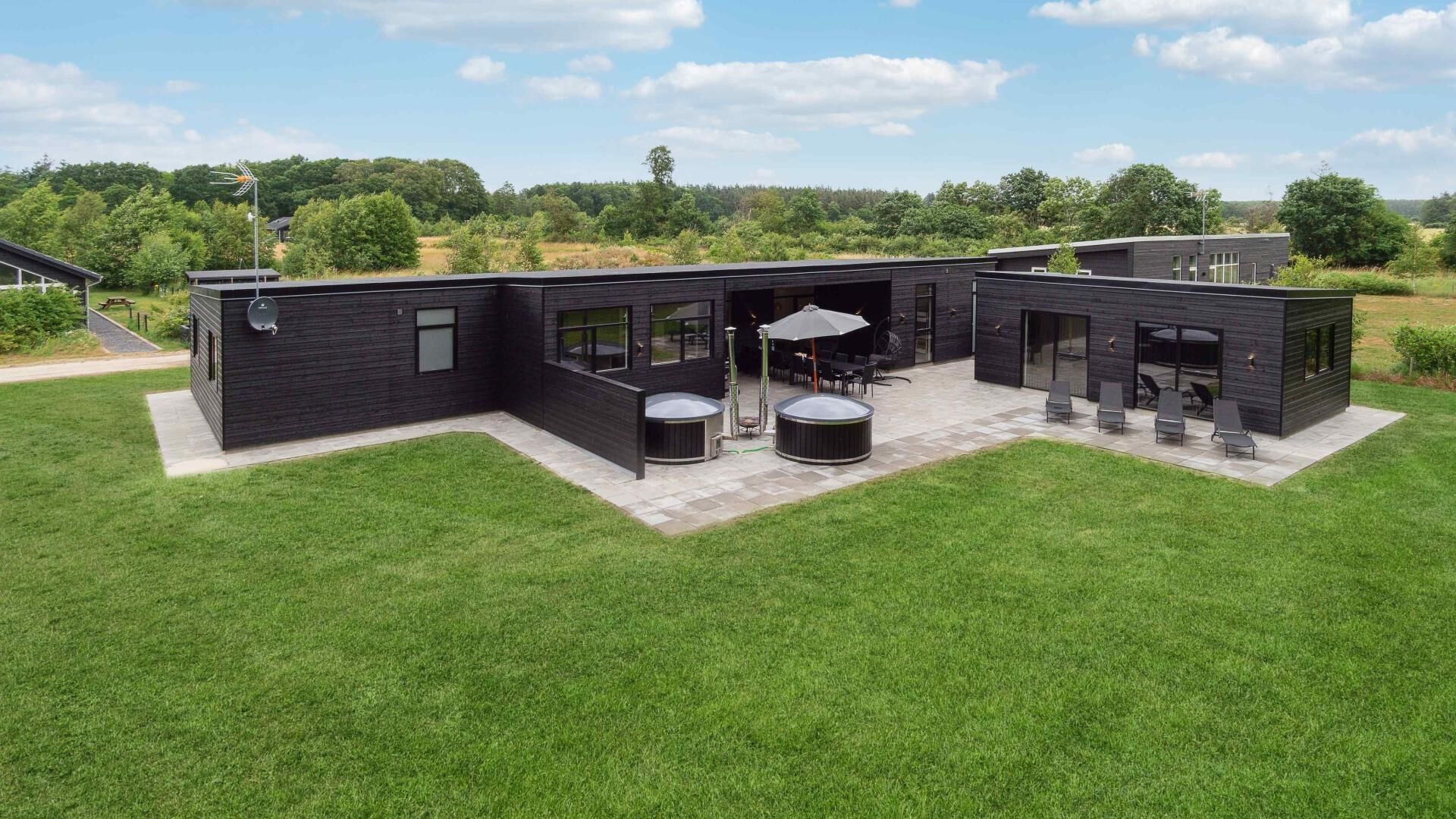 A modern house with a patio area, two hot tubs, and a covered seating area.