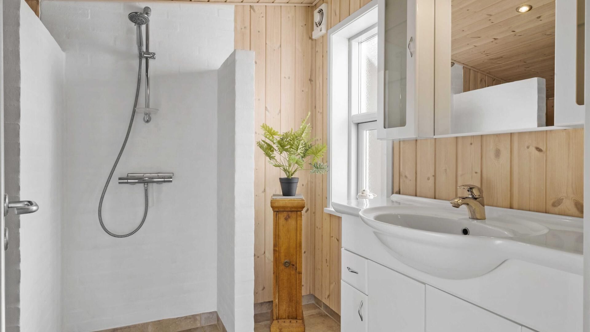 Ein Badezimmer mit Dusche, Waschbecken und Holzvertäfelung.