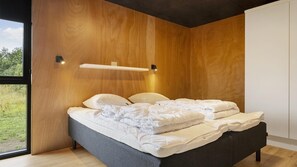 A modern bedroom with a bed, wooden panel walls, a window, and a shelf.