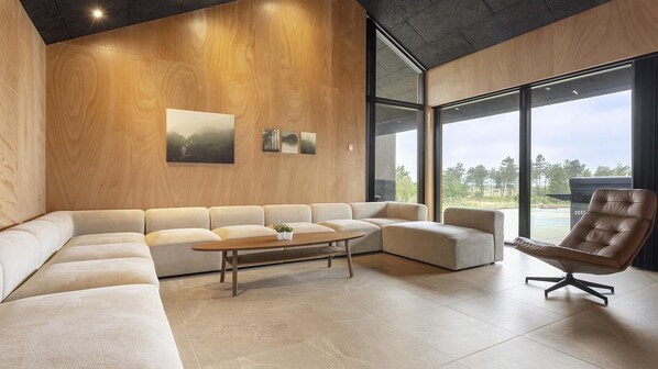 A modern living room with a sectional sofa, a coffee table, and a leather armchair.