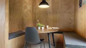 A corner seating area with a wooden wall, a table with a plant, a cup, and a muffin, and a bench.