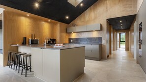 A modern kitchen with a central island, bar stools, a microwave, and a coffee machine.