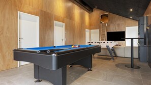 A pool table in a room with wooden walls and a tiled floor.