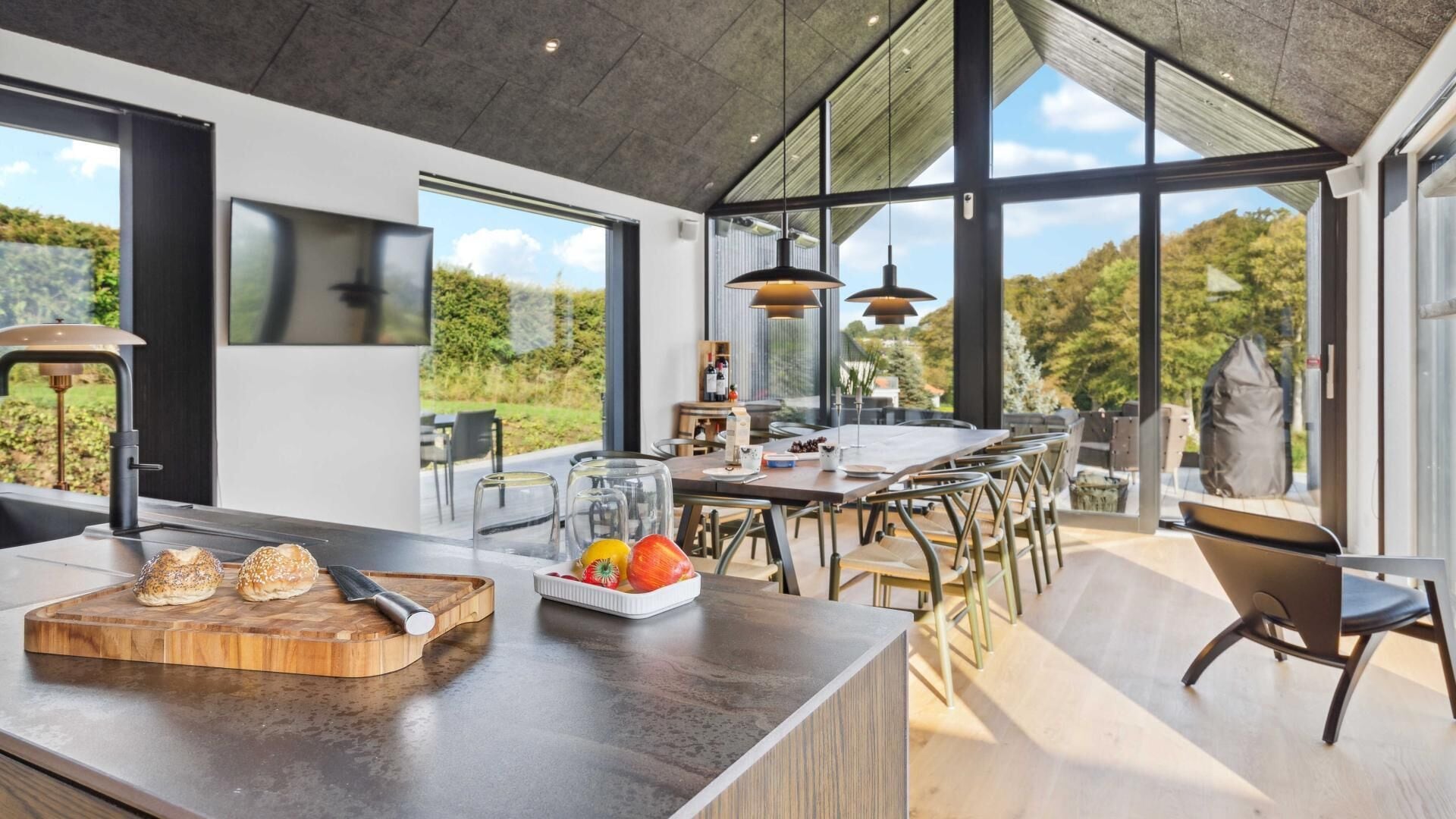 Een moderne keuken met een groot schiereiland, een eethoek en grote ramen met uitzicht op de omgeving.