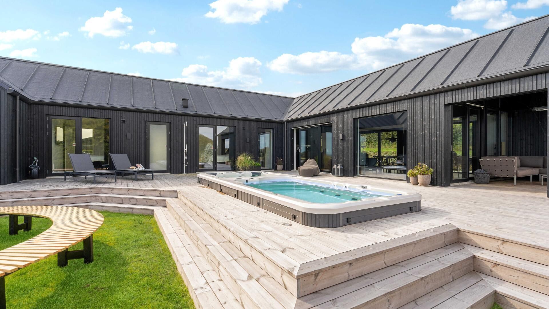 Ein moderner Poolbereich im Freien mit Whirlpool, Holzterrasse und Sitzgelegenheiten.