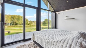 A bedroom with a large window, a bed, and a view of a green landscape. - VillaVilla 992 - Hejlsminde, Sydjylland (Hejls)