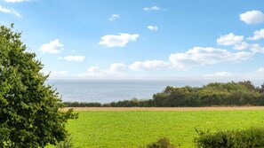 A coastal landscape with a field, trees, and a view of the sea. - VillaVilla 992 - Hejlsminde, Sydjylland (Hejls)