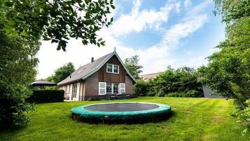 Een huis met een verzorgd gazon en een trampoline in de tuin.