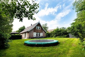 A house with a well-maintained lawn and a trampoline in the yard. - Holiday home with 2 bedrooms (Appelscha)