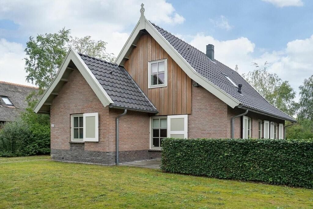 Een tweelaags huis met een schuin dak, een bakstenen gevel en een verzorgd gazon.